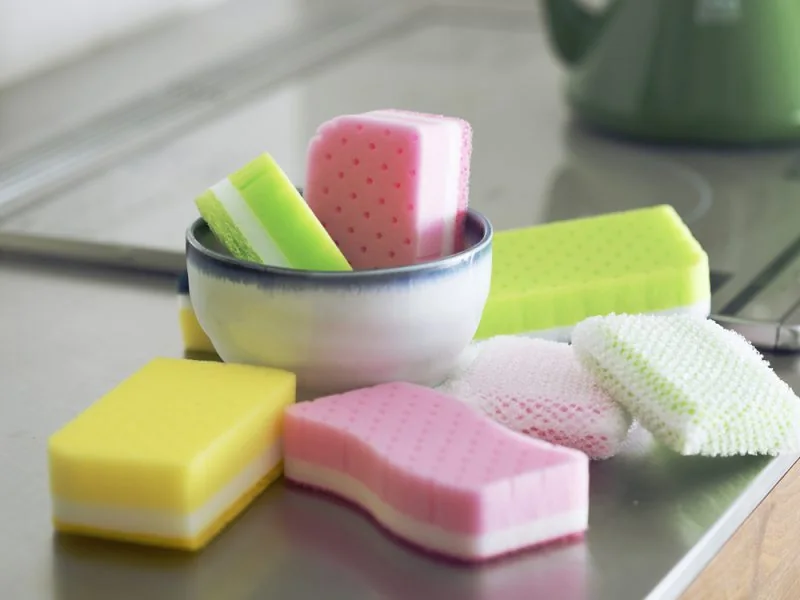 Colourful kitchen sponges in and around a bowl