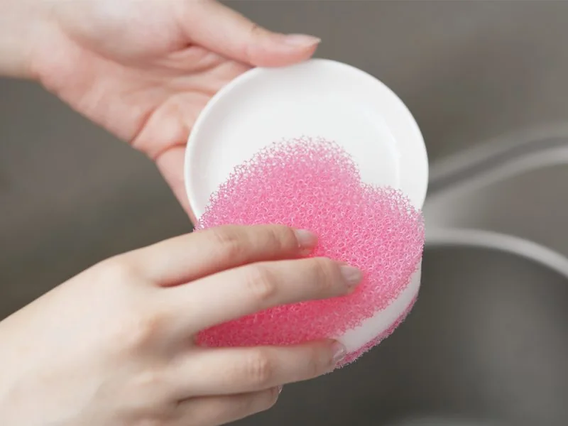 Washing a bowl with a round pink sponge