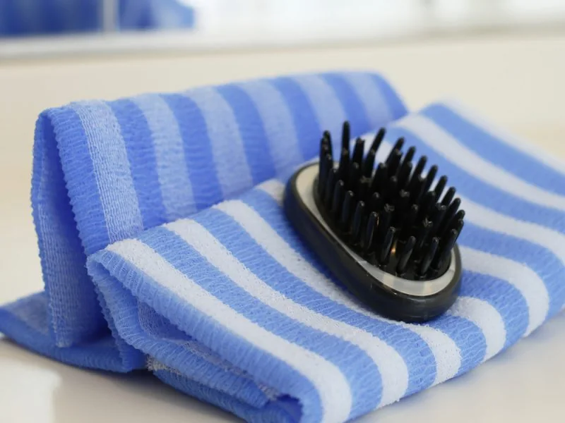 A scalp-care brush on striped towels