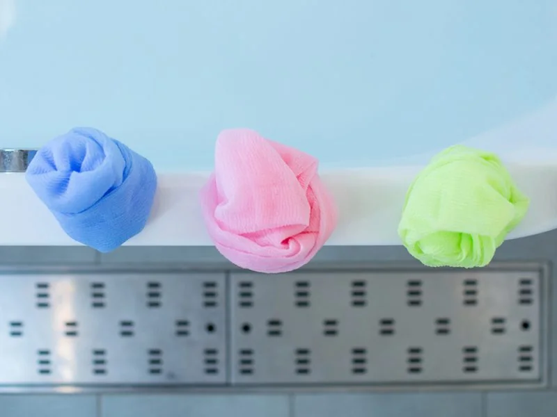 Blue, pink and green shower balls on the edge of a bath