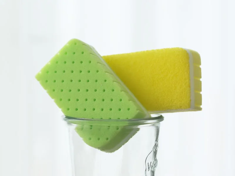 Green and yellow kitchen sponges in a glass