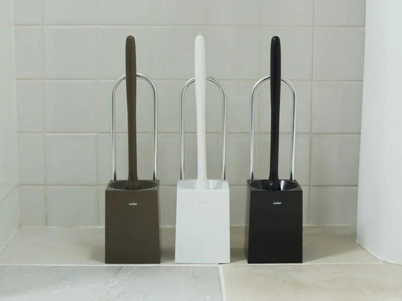 Three toilet brushes in holders, in brown, white and black