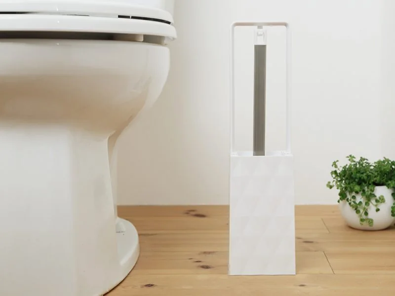 A slim toilet brush stand beside a toilet