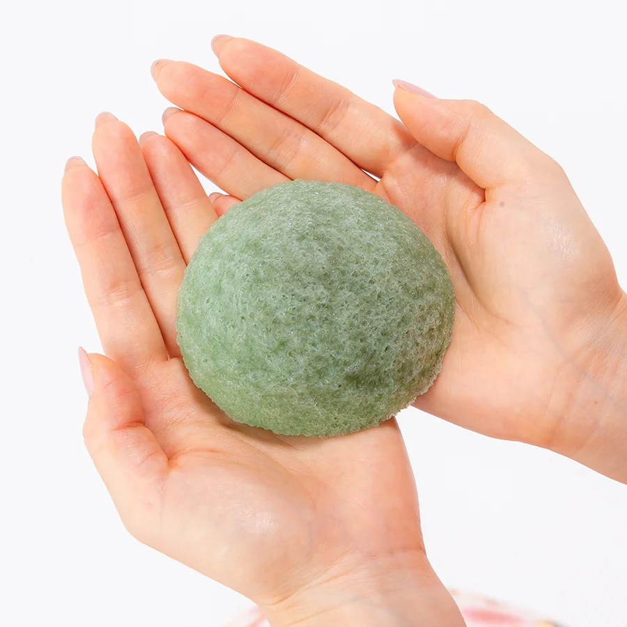 Green tea konjac face sponge held in two hands