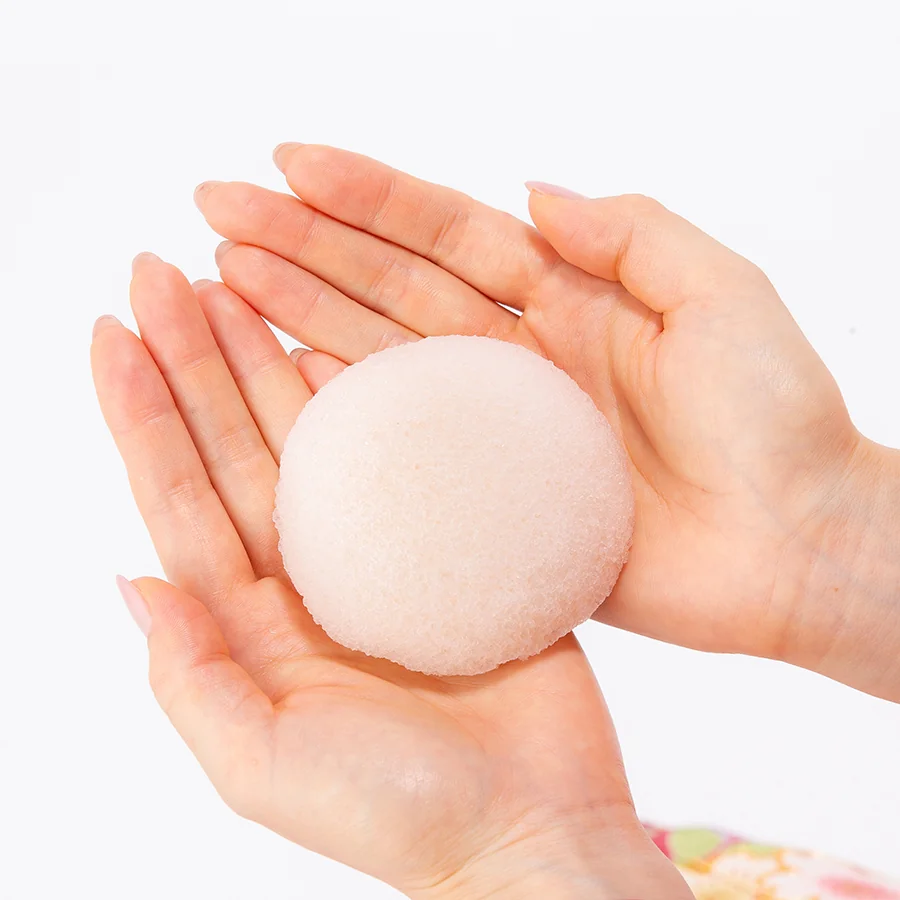 White peach konjac face sponge held in two hands