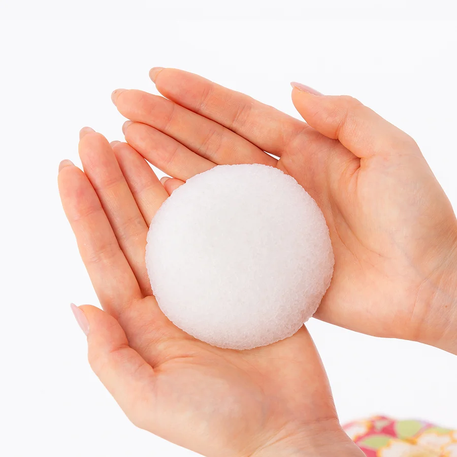 White konjac face sponge held in two hands