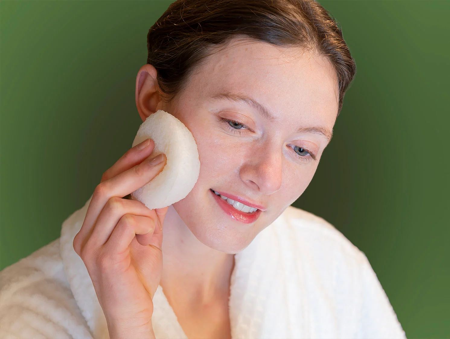 A person washing their face with a white konjac sponge