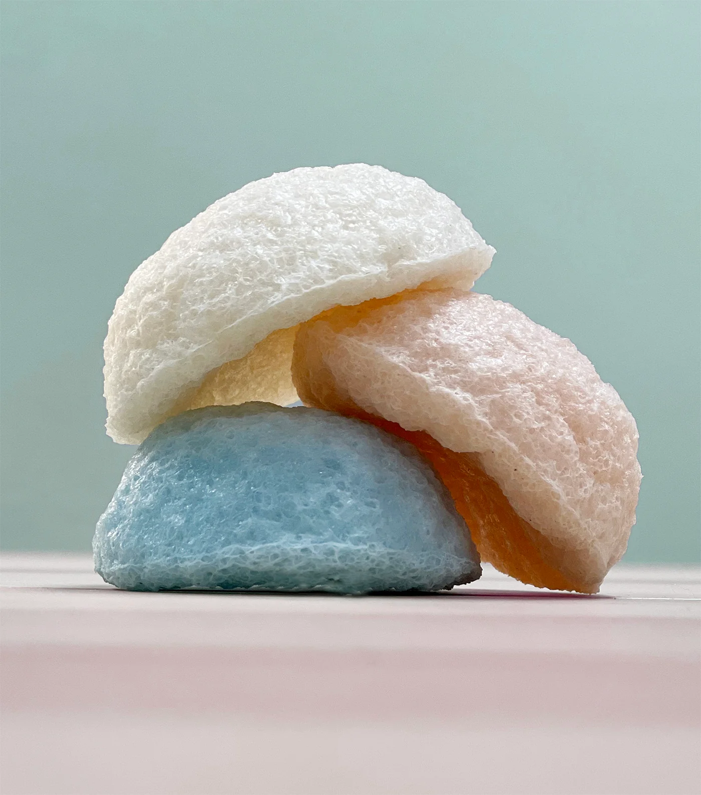 Three konjac face sponges stacked on a pale background